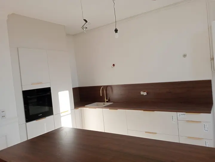 Plan de travail et crédence en bois foncé d'une cuisine blanche
